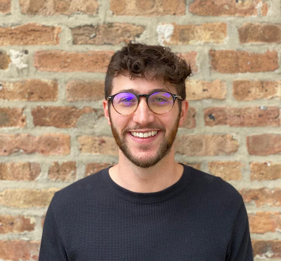 Image of Aaron Chasan, a white man smiling with brown hair, glasses, and a beard